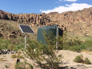 Solar water pumps - tank near rocky landscape.